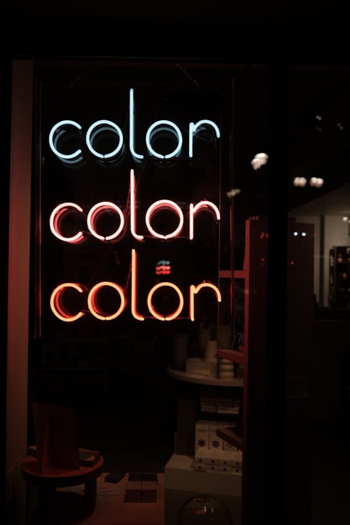 A modern neon sign with the word 'color' glowing inside a shop display at night.